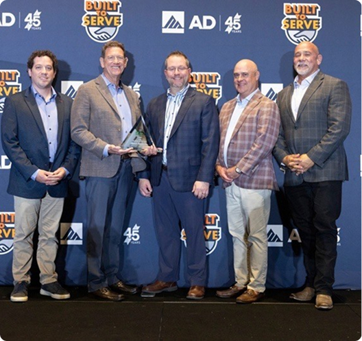Merit Brass team members on stage accepting the 2026 AD PVF Supplier of the Year award